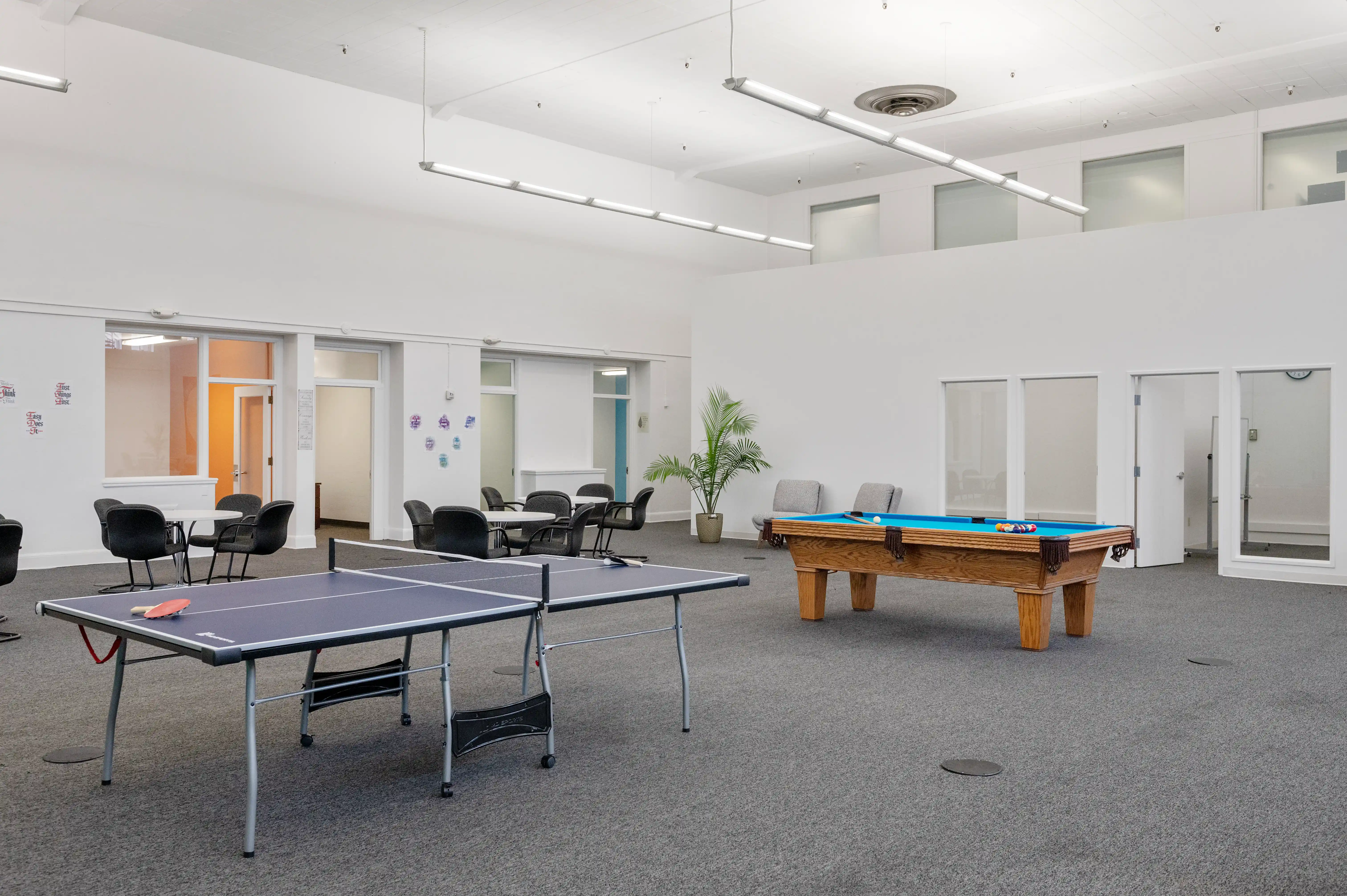 Activity room with ping pong table, pool table, and group seating areas at Atlas Treatment Center