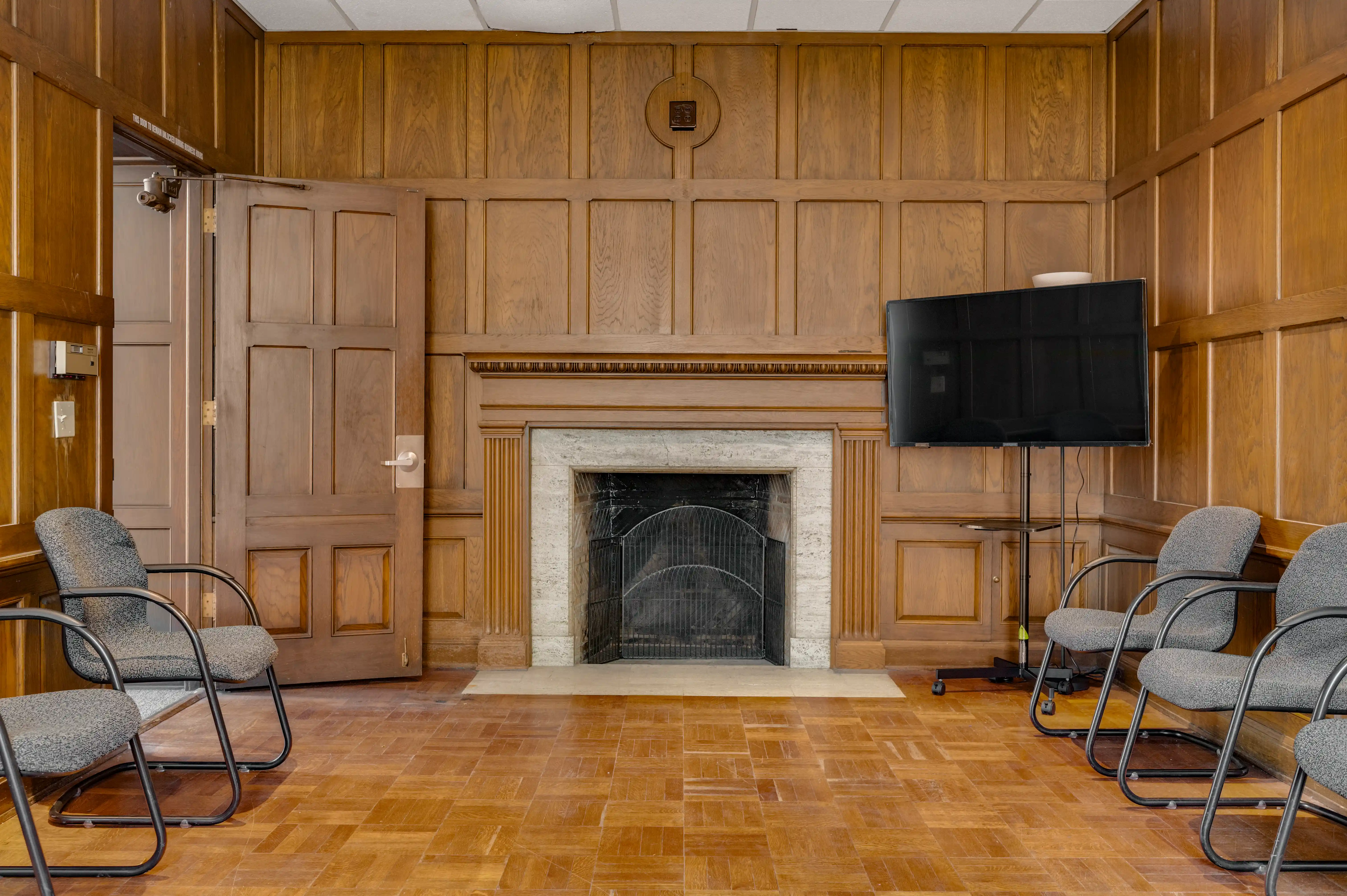 Wood-paneled group therapy room with marble fireplace and circle seating at Atlas Treatment Center
